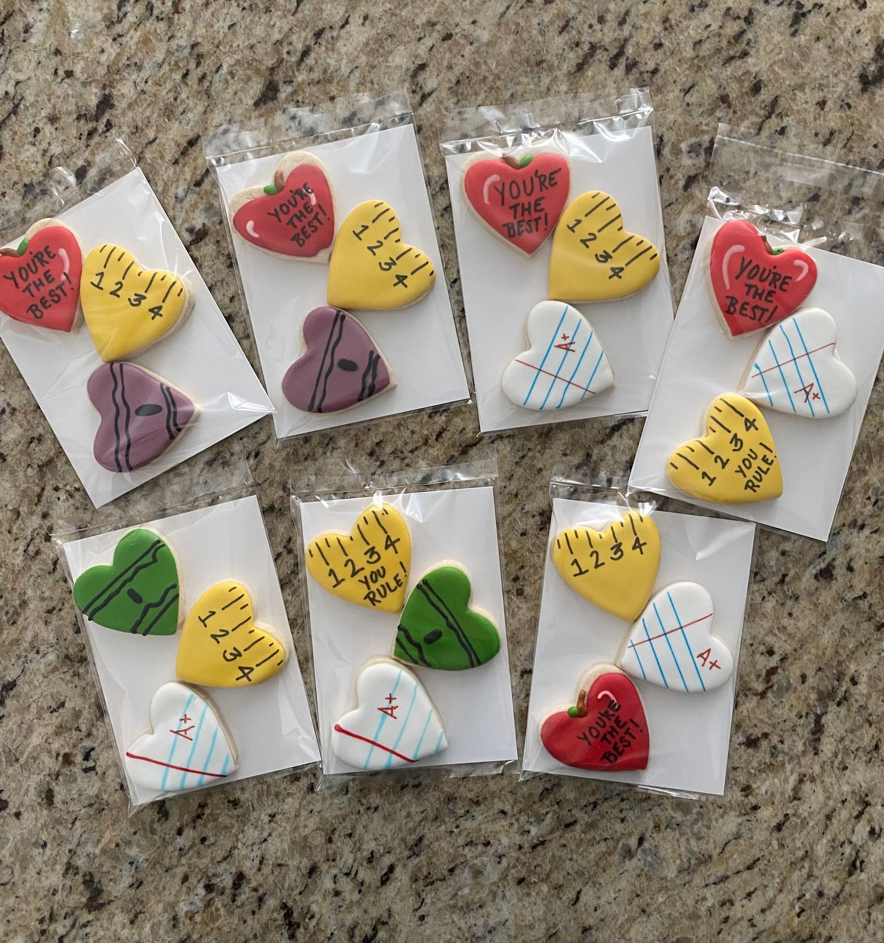 Decorative cookies shaped like hearts with school-themed icing designs, including rulers and apples.