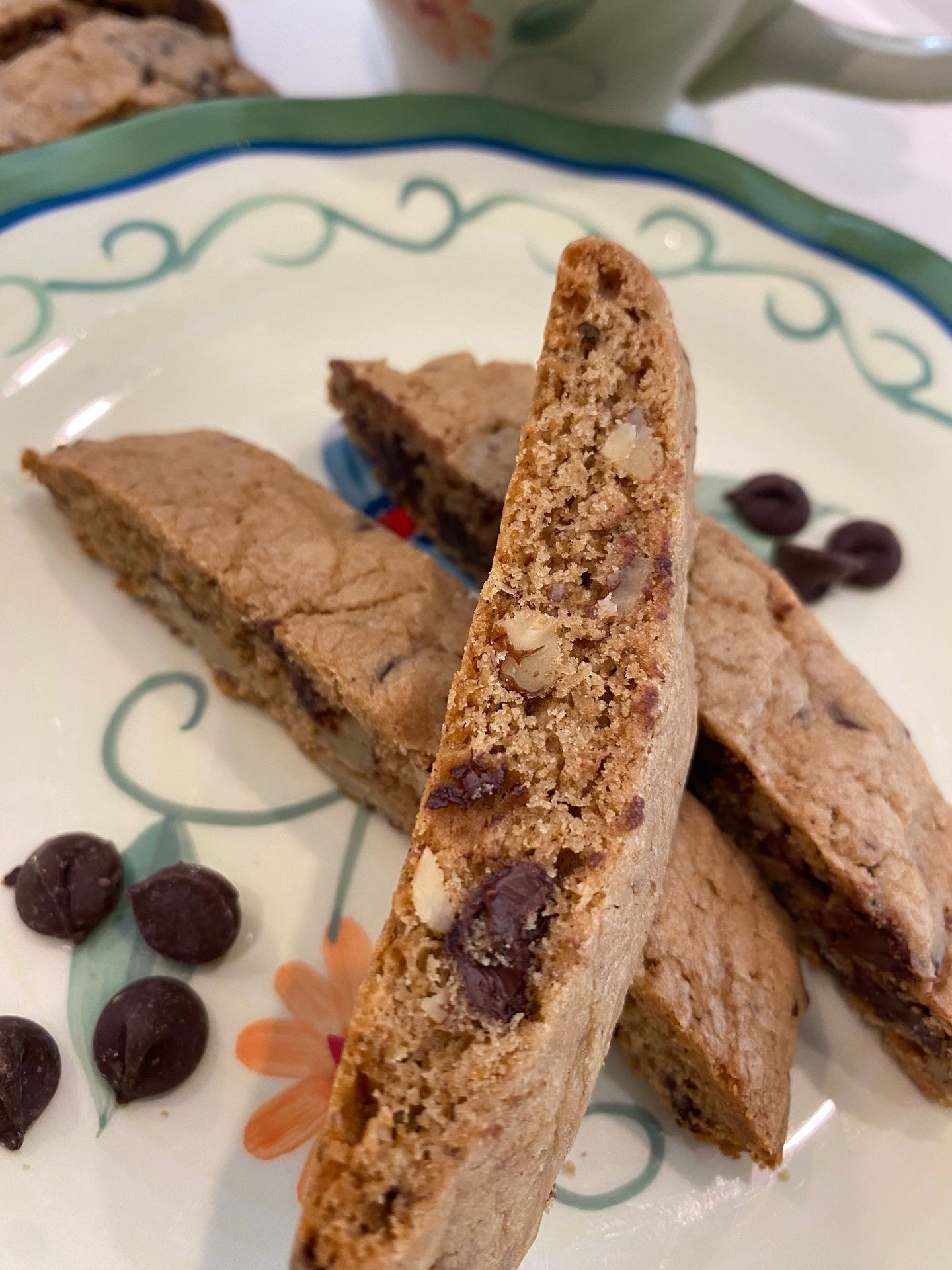 Plate with chocolate chip biscotti and chocolate chips, floral design visible on the plate.